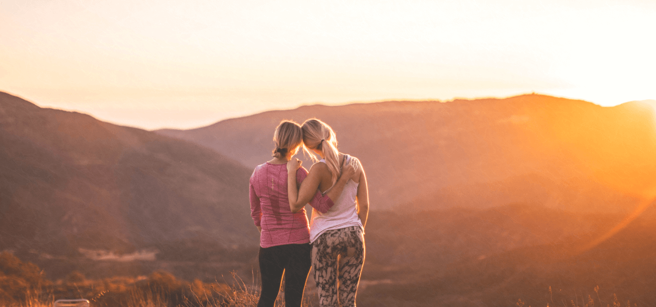 山の上で夕日を眺める外国人女性2人