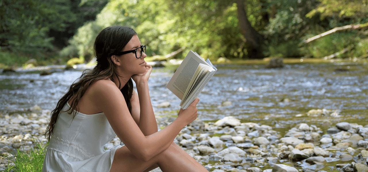 河原で本を読む大学生