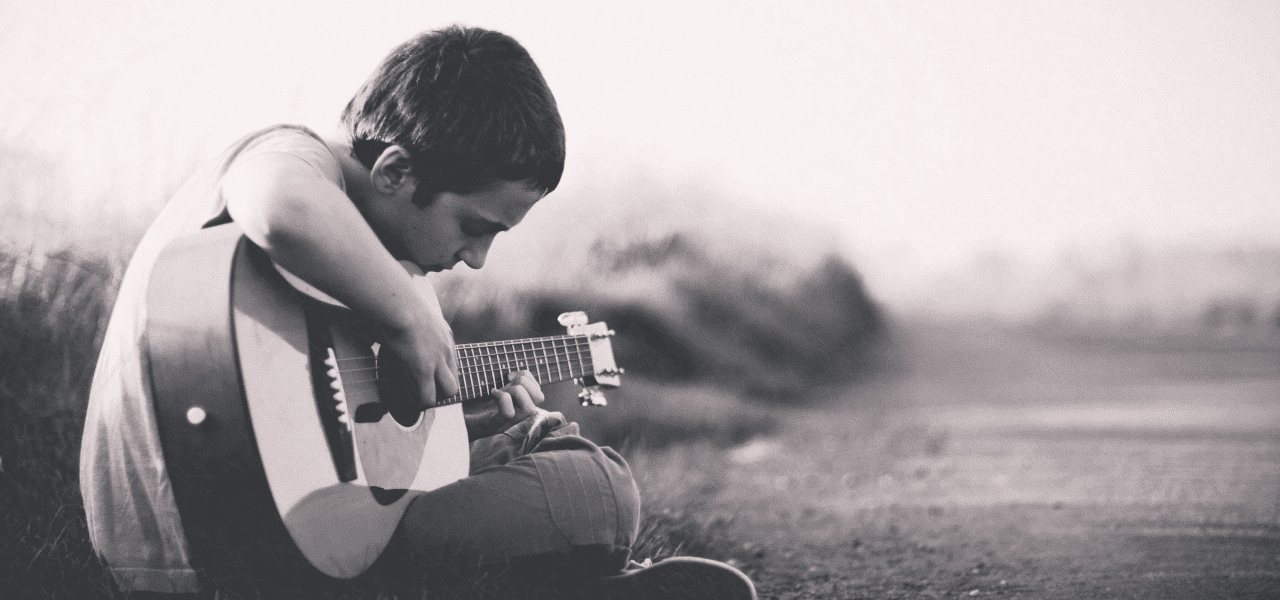木陰で趣味のギターを弾く男の子